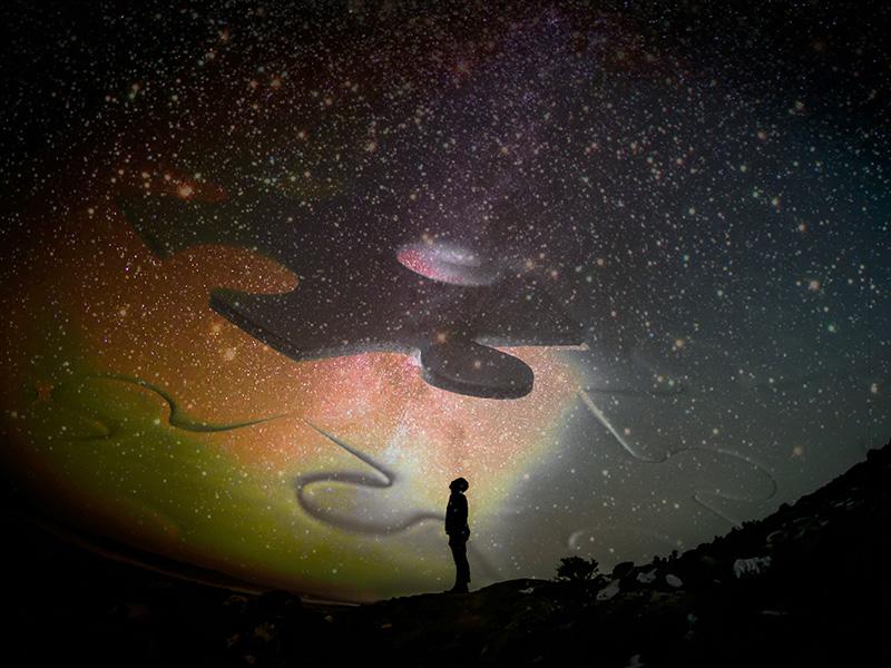Person looking up at puzzle in sky at night.